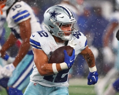 Cowboys' Deuce Vaughn, dressed in a white and blue uniform, sprints with the ball during a game.