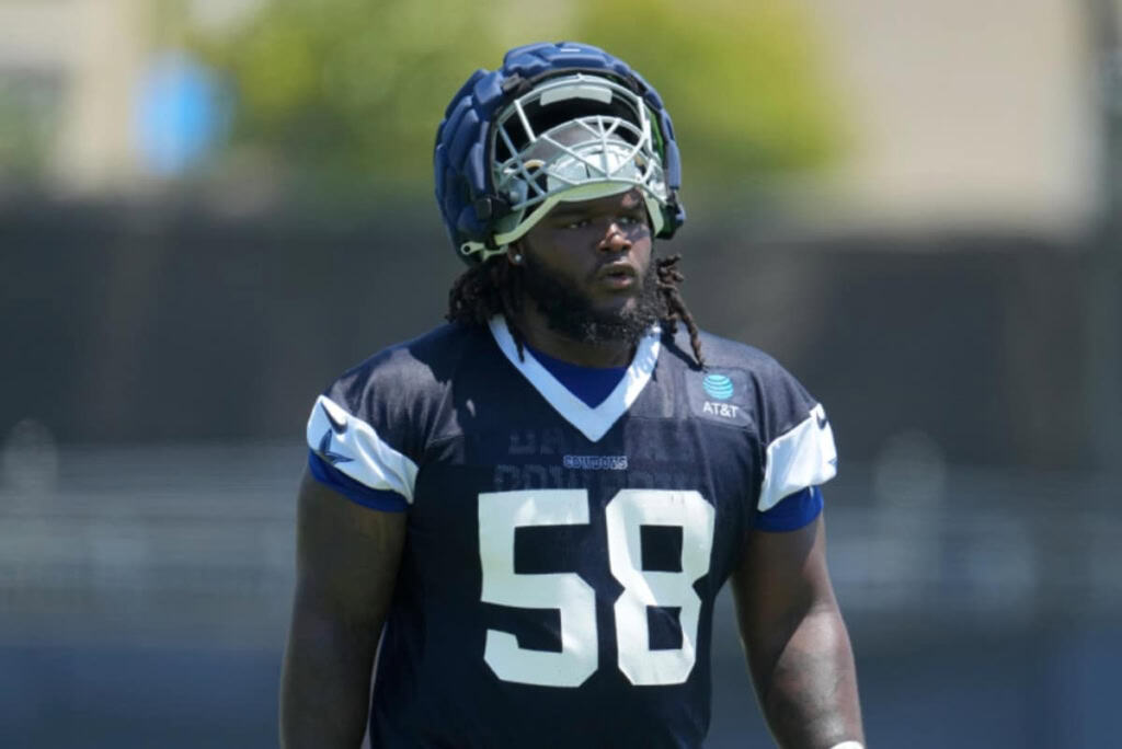 Football player in navy and white gear and helmet, numbered 58, stands on the field with a focused expression.