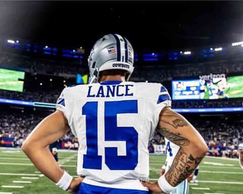 Football player with "Lance" and number 15 on jersey stands with hands on hips, facing a stadium full of spectators.