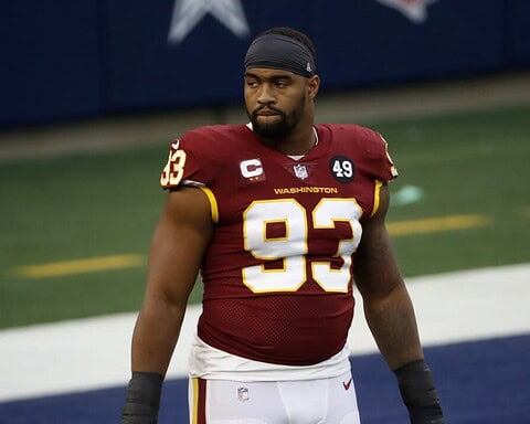 Football player in a red jersey with number 93 stands on the field with a serious expression.