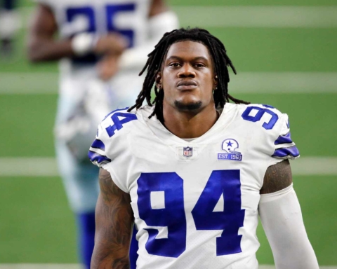 A football player wearing a white jersey with the number 94, standing on the field.