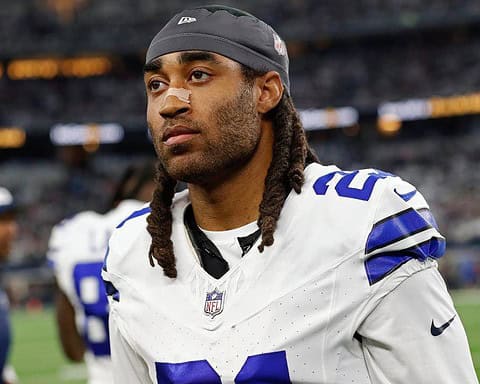 A football player in a white uniform with the number 21 stands on the field, looking ahead.