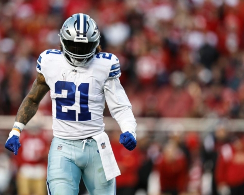 Football player in a blue and white uniform, wearing number 21, walking on a field with a crowd in the background.