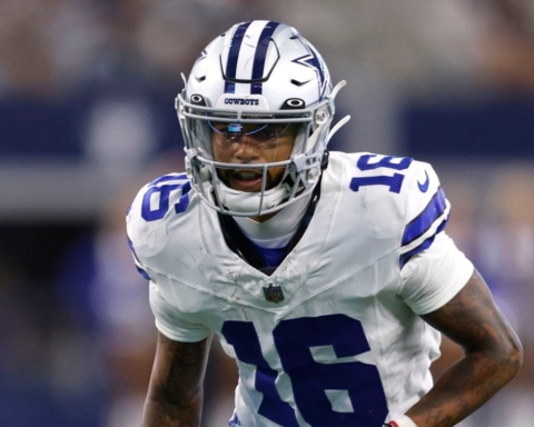 Football player in a blue and white uniform, wearing a helmet marked with "Cowboys," on the field during a game.