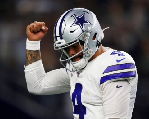 Football player in a Dallas Cowboys uniform raises his fist in a celebratory gesture during a game.