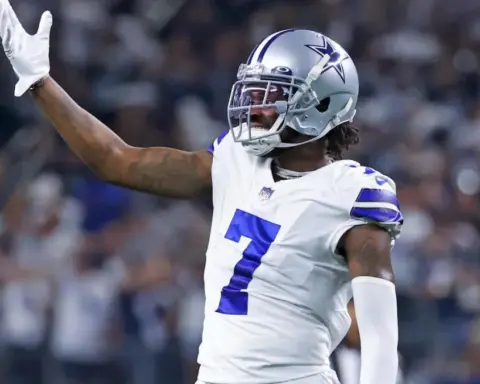 Football player wearing a white and blue Dallas Cowboys uniform with the number 7 raises his left arm during a game.
