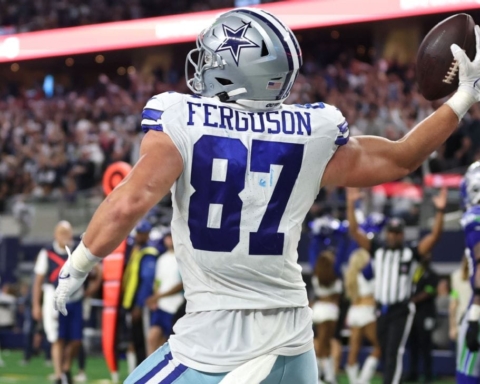 Football player with jersey number 87 celebrates holding the ball on the field with fans in the stadium.