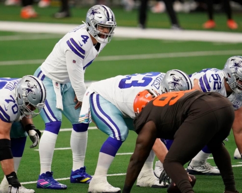 Football players from the Cowboys and Browns teams are lined up at the line of scrimmage during a game.