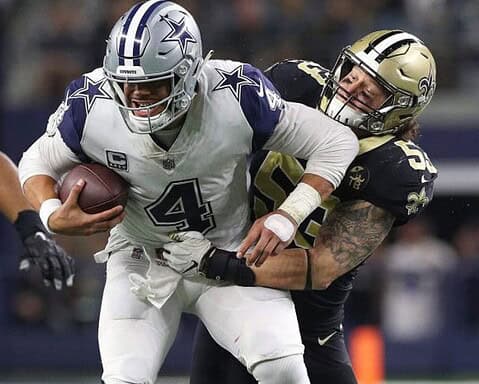 Football player in a white jersey is being tackled by a player in a black jersey during a game.