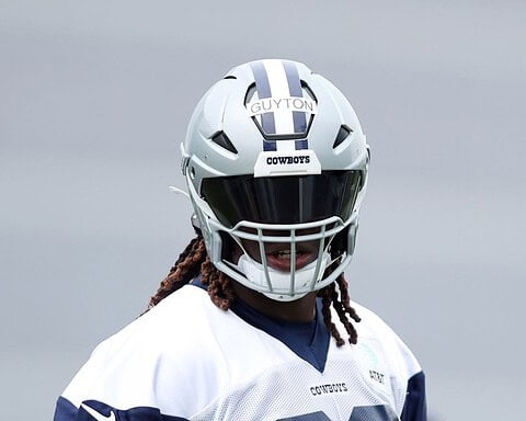 A football player in a Cowboys helmet with a tinted visor and a jersey labeled "GUYTON.