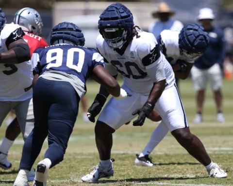 Football players, including Tyler Guyton, in padded gear are practicing diligently on the field.