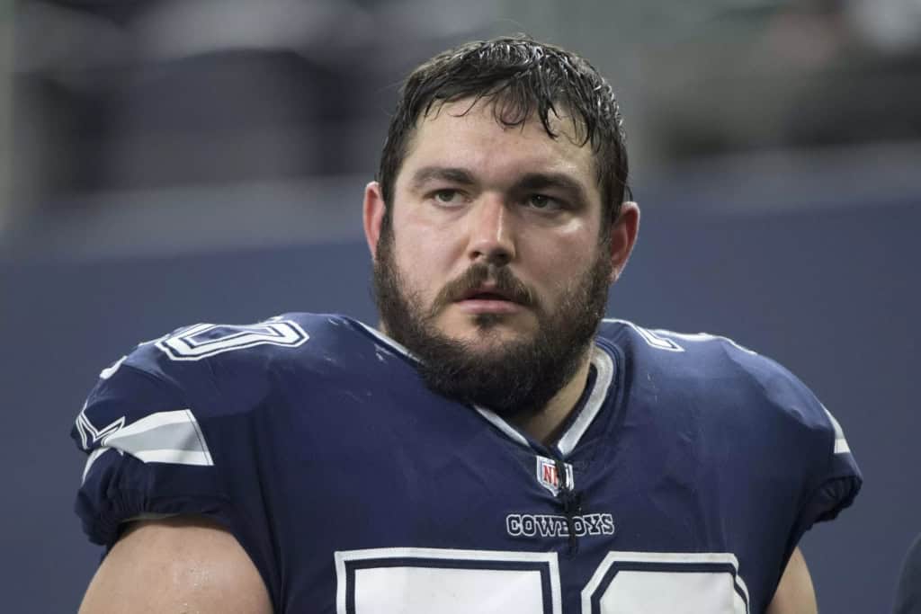 A football player, reminiscent of iconic Cowboys players, stands on the field wearing a navy and white jersey.