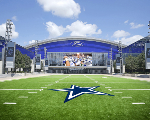 Front view of the Ford Center with the iconic Dallas Cowboys star logo on the green field, basking under a clear blue sky during Week 7.