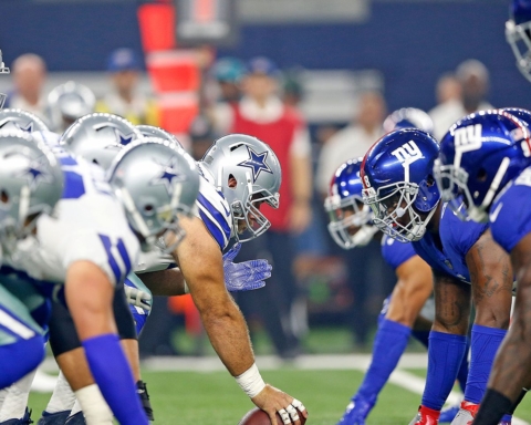 Football players in blue and white uniforms face off at the line of scrimmage during a Dallas Cowboys game.