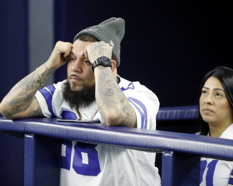 A man and woman in sports jerseys intently watch the DAL vs SF game, their faces tense and focused.