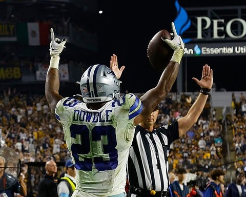 Football player celebrating a touchdown as a referee signals in a crowded stadium.