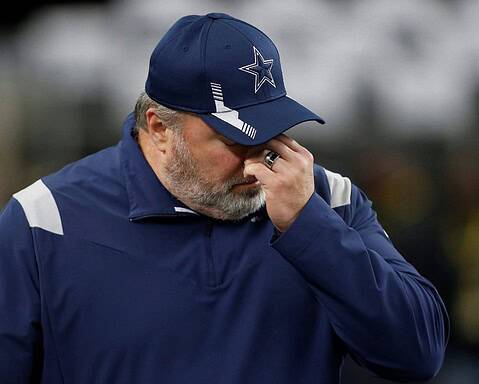 A person in sports attire, perhaps a nod to the Cowboys during their final season, wears a baseball cap and covers their face with one hand.