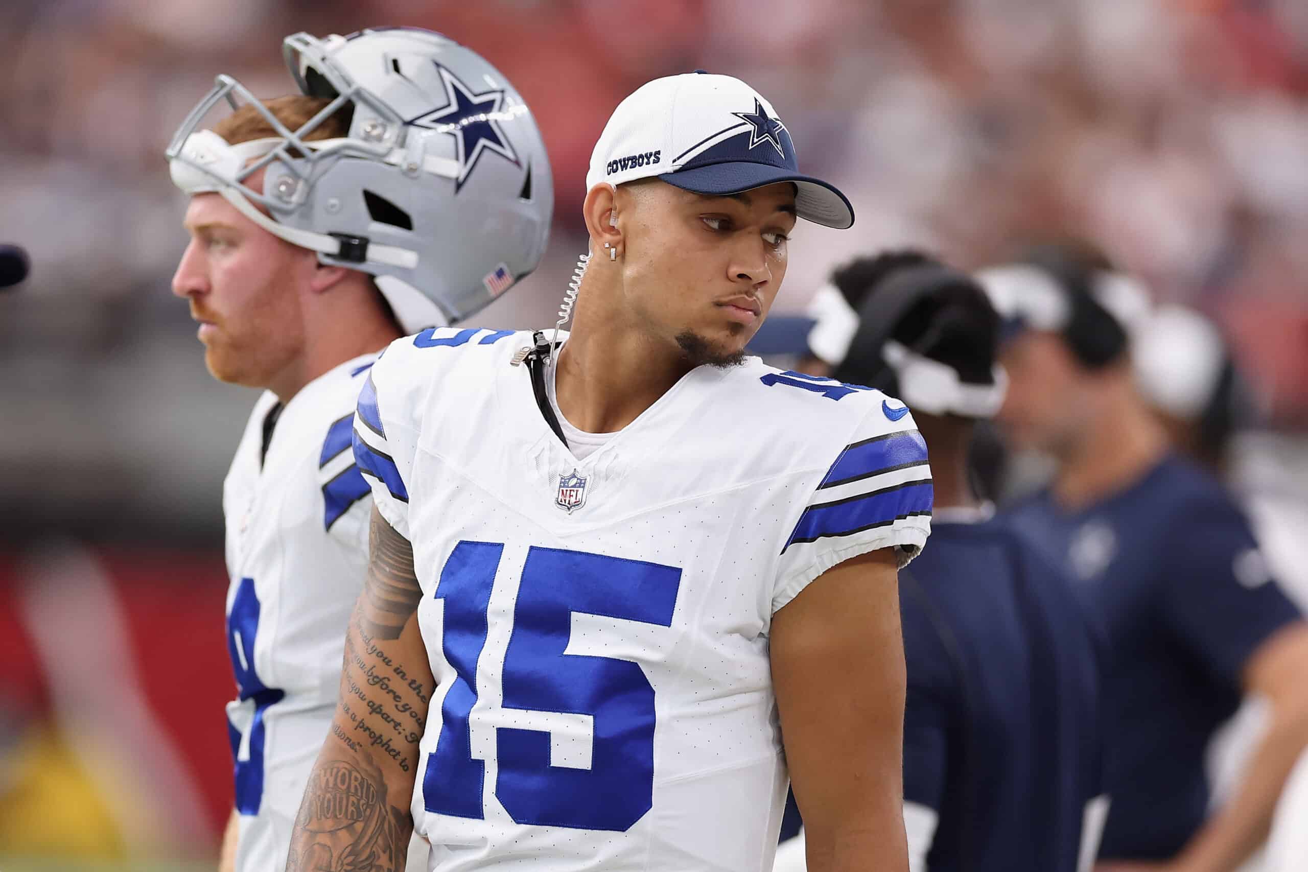 Two Cowboys football players in white uniforms and caps stand on the sideline during the game, embodying the "Just Play the Man" spirit. Cowboys, Just Play the Man