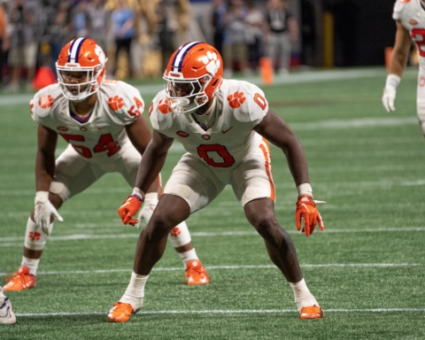 Football players in white uniforms, reminiscent of the Dallas Cowboys, focus intently on the action unfolding on the green field.