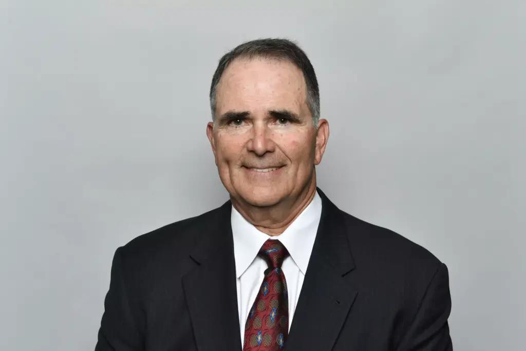 A man in a suit and tie, smiling confidently, appears ready to tackle any challenge, much like a strategic player among the Cowboys.