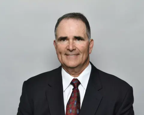 A man in a suit and tie, smiling confidently, appears ready to tackle any challenge, much like a strategic player among the Cowboys.