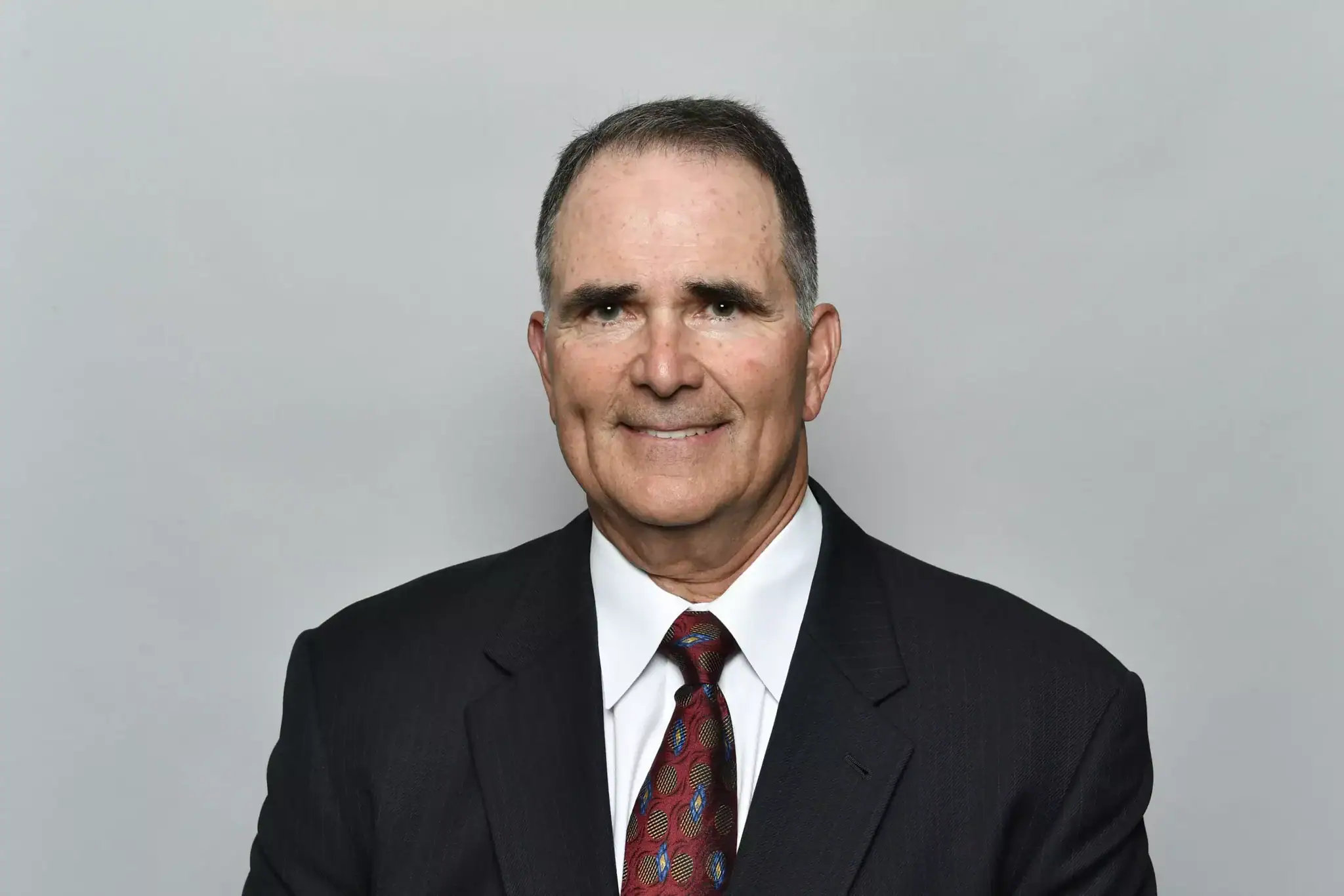 A man in a suit and tie, smiling confidently, appears ready to tackle any challenge, much like a strategic player among the Cowboys.