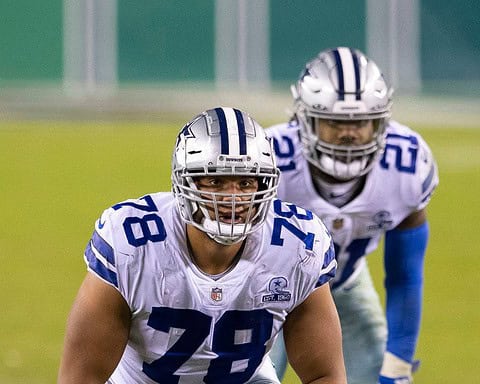 Two veteran football players from the same team stride confidently onto the field, donning their blue and white uniforms and helmets, ready to tackle the challenges of the 2024 season.
