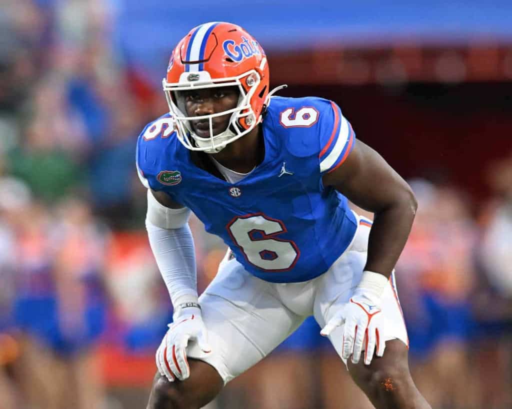 Dominant football player in Florida Gators uniform, wearing number 6, in a ready stance during a game, representing college football at its best.