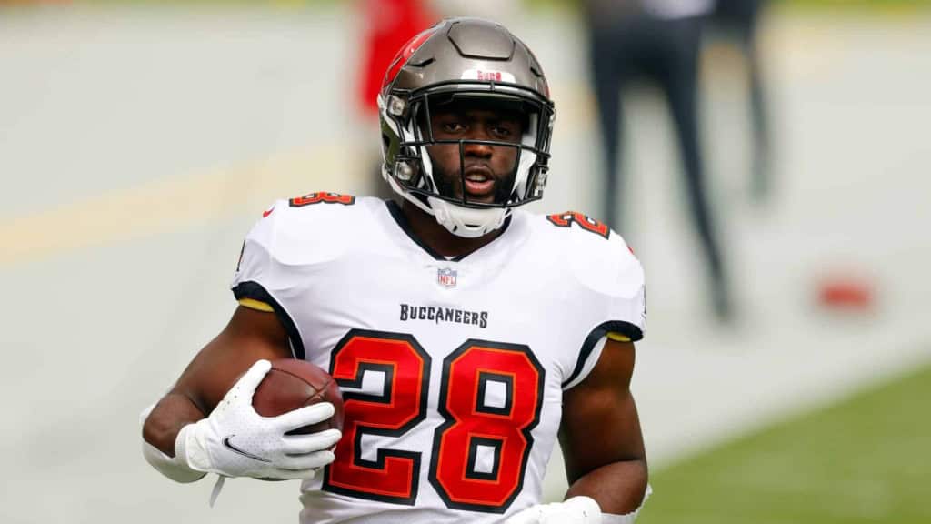 NFL player in Tampa Bay Buccaneers uniform holding football on field.