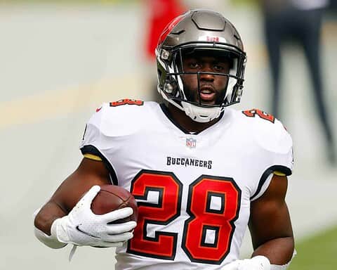 NFL player in Tampa Bay Buccaneers uniform holding football on field.
