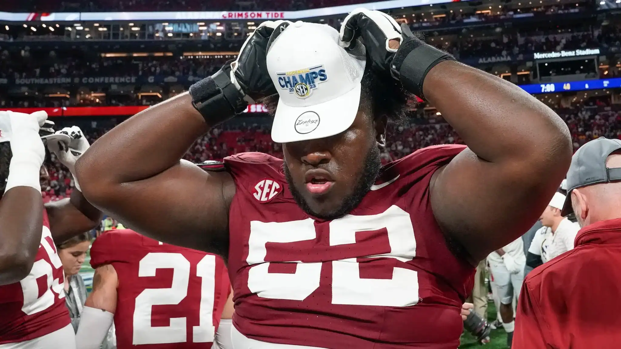 Inside the Star football player wearing a red jersey and white cap celebrating victory after winning the SEC Championship at Mercedes-Benz Stadium.