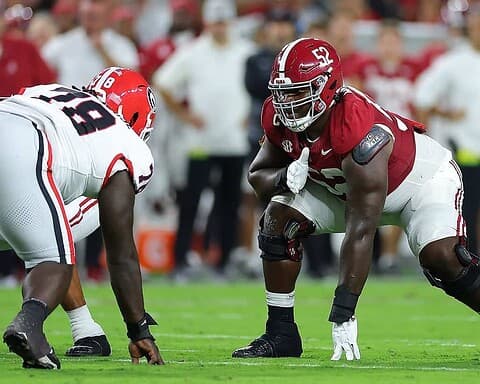 Alabama Crimson Tide football players lining up on the field during a game, showcasing intense athleticism and team strategy.
