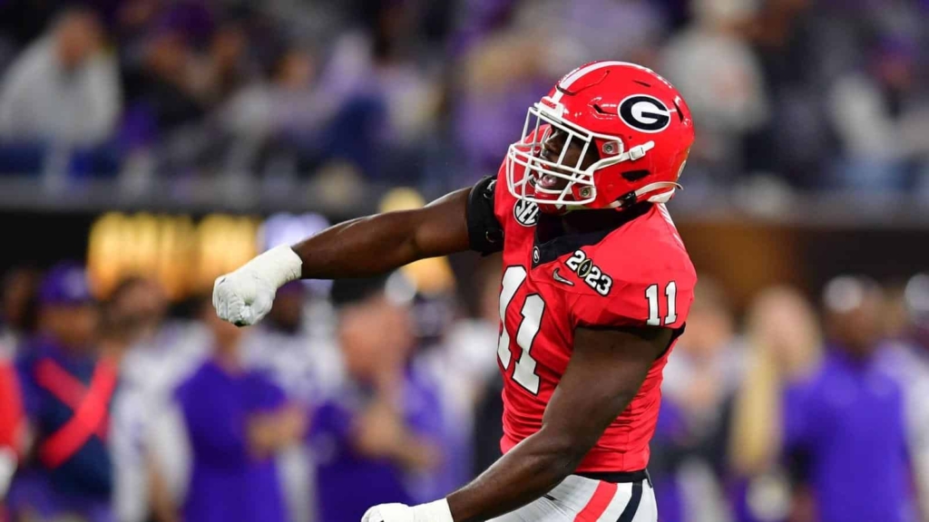 Athlete in red Georgia Bulldogs football uniform celebrating during game 2023.