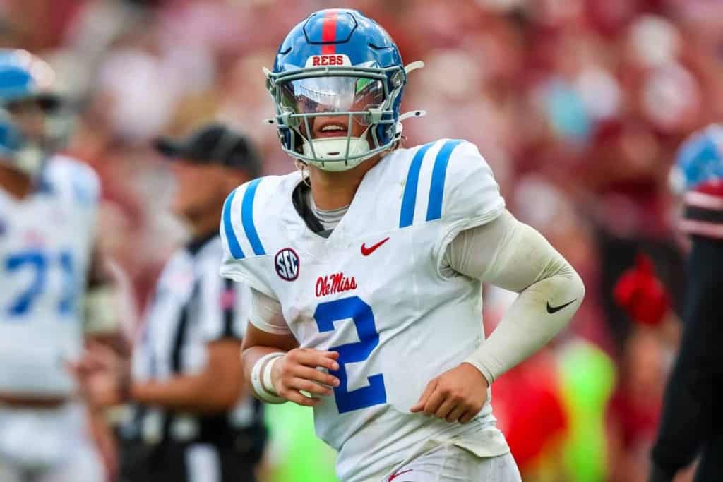 Fast football player in a white and blue uniform with a helmet, playing for Ole Miss Rebels, during an NCAA college football game.