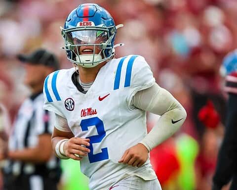Fast football player in a white and blue uniform with a helmet, playing for Ole Miss Rebels, during an NCAA college football game.