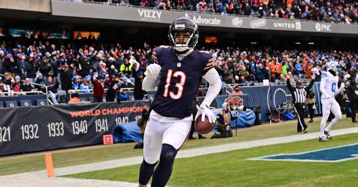Wide receiver in Chicago Bears uniform celebrating touchdown on the field during NFL game, with cheering crowd in the background.