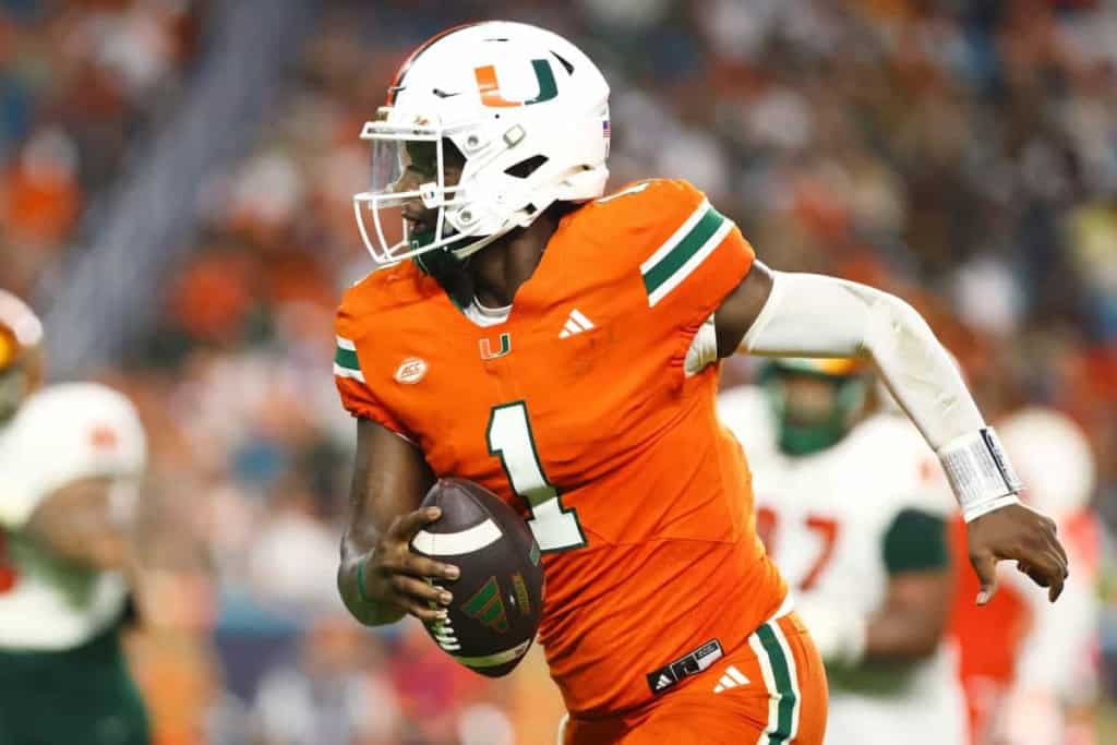 Miami Hurricanes football player in orange jersey with number 1, running with football during game on field.