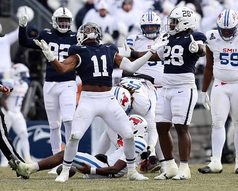 Throwing a touchdown pass during an intense college football game, showcasing team spirit and athletic performance on the field with players in inside the star uniforms.