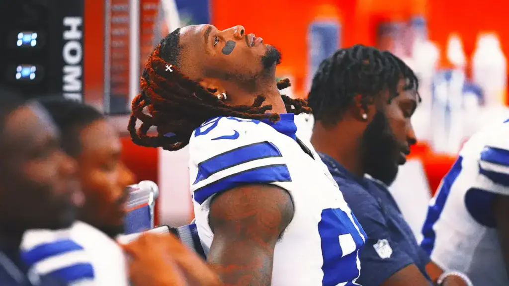 Competitive Dallas Cowboys football players during a team meeting, showcasing team unity and focus. The players are dressed in their game jerseys, sitting in the locker room emphasizing team preparation and camaraderie.