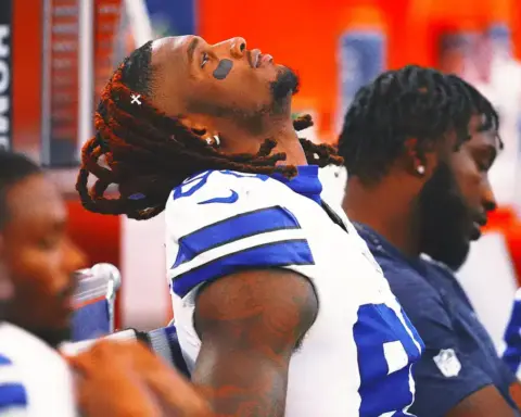 Competitive Dallas Cowboys football players during a team meeting, showcasing team unity and focus. The players are dressed in their game jerseys, sitting in the locker room emphasizing team preparation and camaraderie.