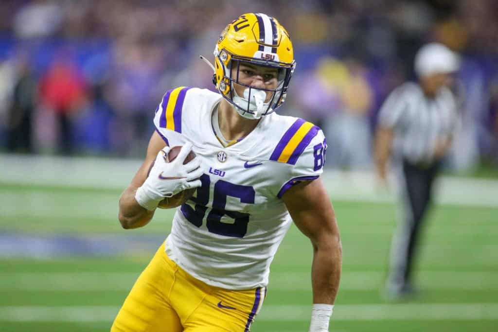 LSU football player in uniform running with the ball during a game against Texas A&M, showcasing college football action and athlete performance.