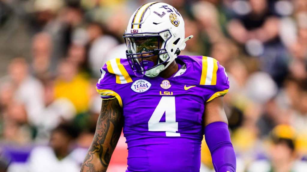 LSU football player wearing number 4 in a purple and gold uniform on the field at a game.