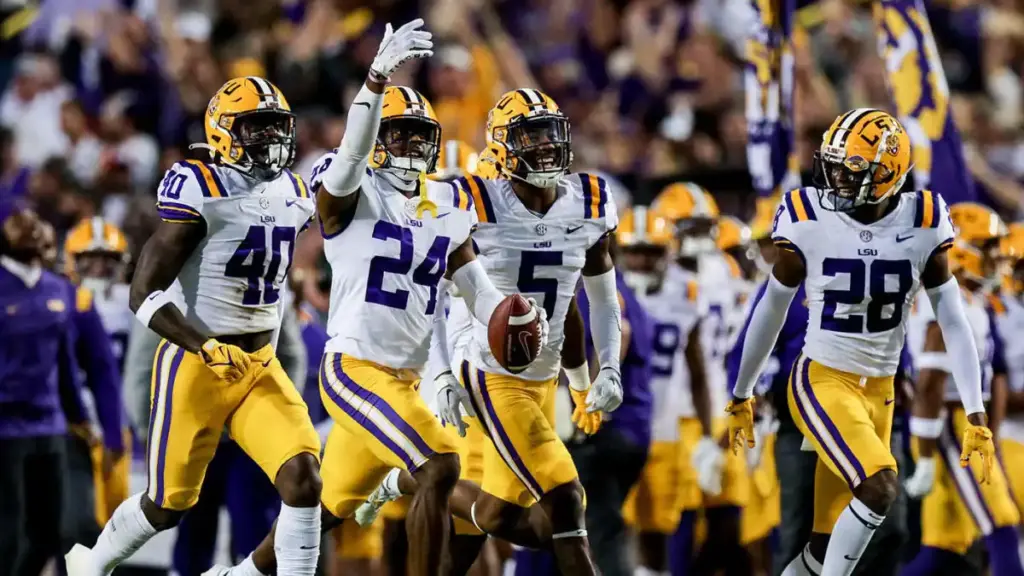 Louisiana State University (LSU) football players celebrating on the field during a game, wearing purple and gold uniforms, showcasing team spirit and athletic excellence in college football.