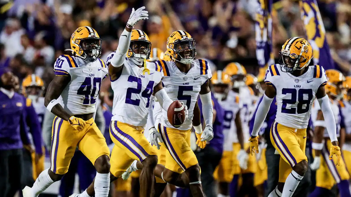 Louisiana State University (LSU) football players celebrating on the field during a game, wearing purple and gold uniforms, showcasing team spirit and athletic excellence in college football.