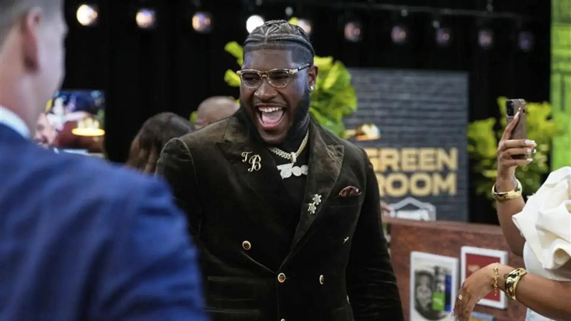 Vibrant celebration at Inside The Star event, featuring a smiling man in stylish black blazer, gold jewelry, and trendy glasses, surrounded by attendees, with a backdrop reading 'Green Room'.