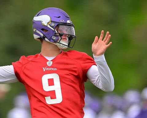 Quarterback in Minnesota Vikings football uniform preparing to throw the football during practice or game.