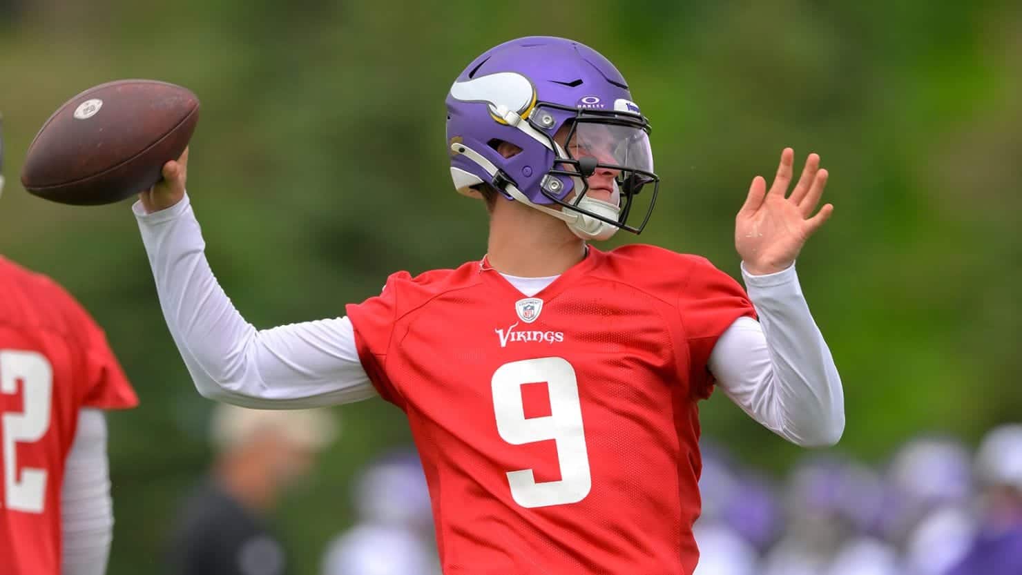 Quarterback in Minnesota Vikings football uniform preparing to throw the football during practice or game.