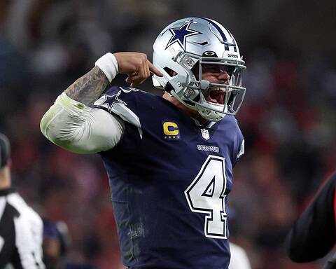 Dallas Cowboys player celebrating on the field, wearing helmet and jersey with number 4, during an NFL game, showing enthusiasm and team spirit.