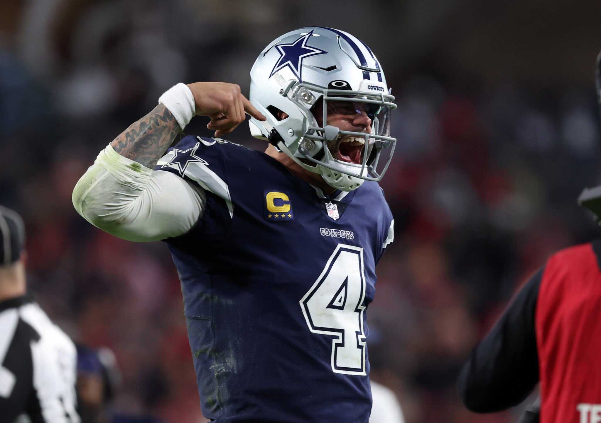 Dallas Cowboys player celebrating on the field, wearing helmet and jersey with number 4, during an NFL game, showing enthusiasm and team spirit.