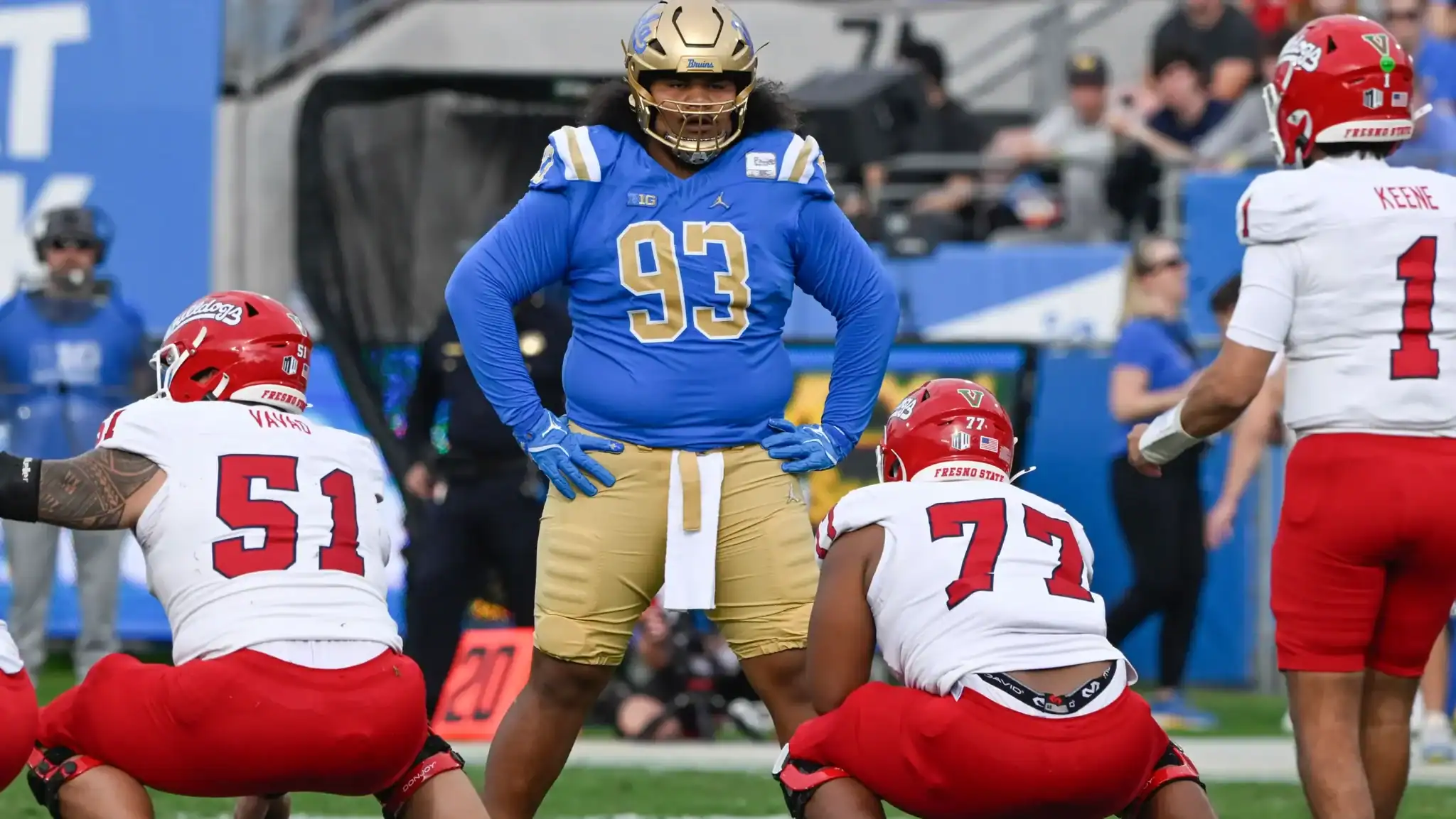 Focus on football players during a game, featuring players from Fresno State and UCLA, with a football game setting, highlighting team uniforms and player stances.